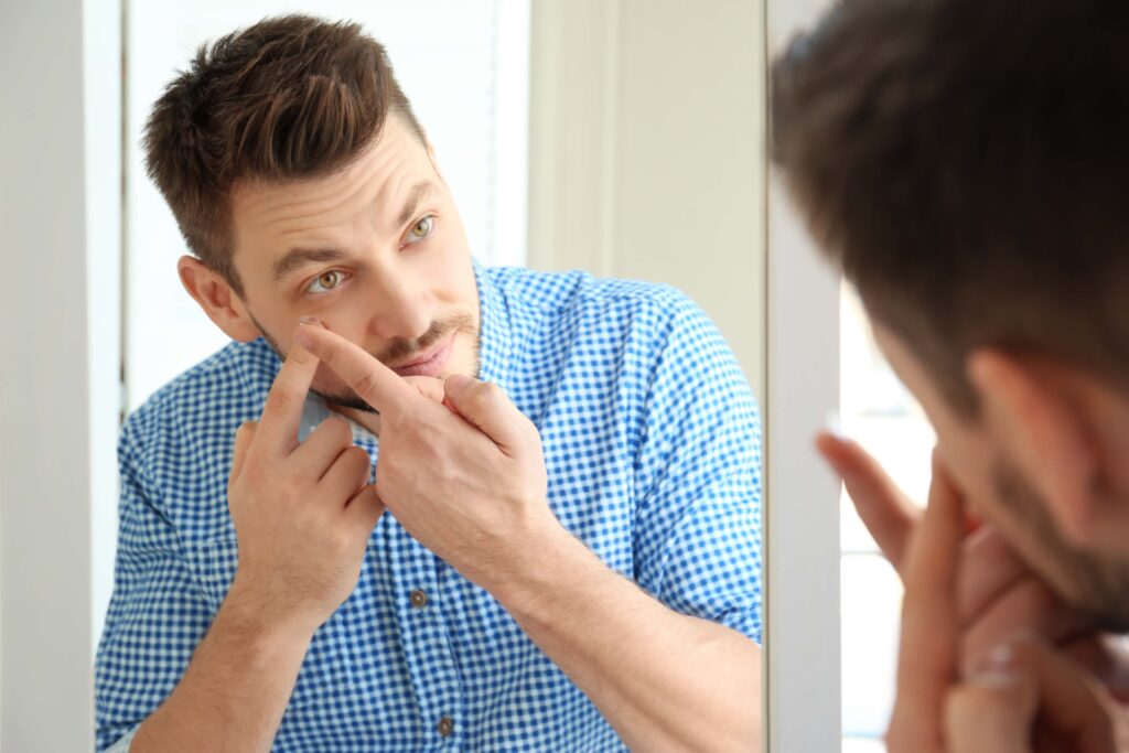 5 Best Extended Wear Contacts Brands 7 man in plaid shirt testing out contact lenses in front of mirror